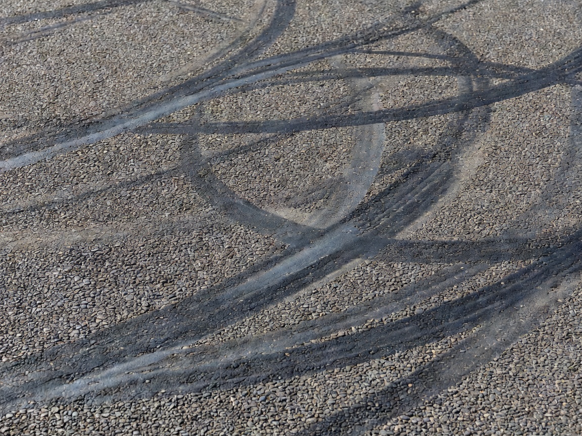 Close-up of aggregate race track asphalt showing micro-texture and tire marbling